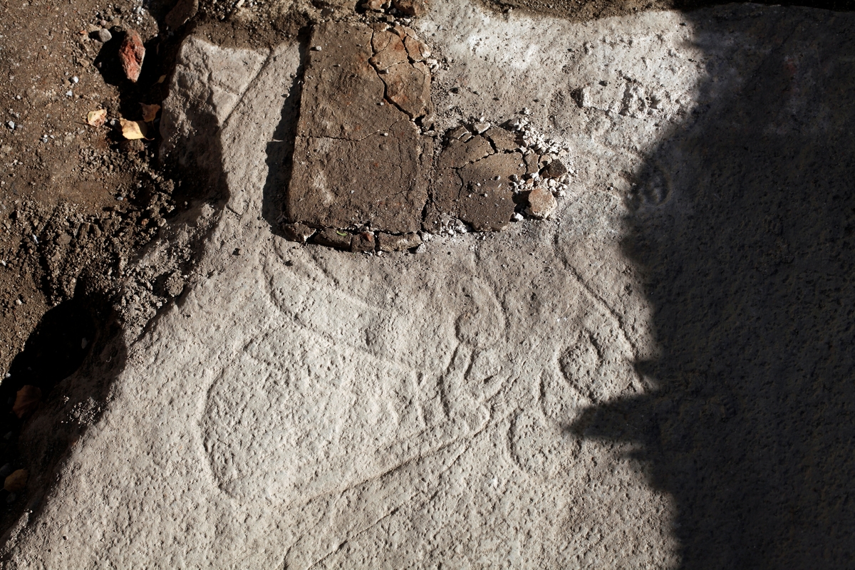 Arkeologisk schaktningsövervakning och undersökning, fågelfiguren som var delvis täckt av kalkbruk, runsten U 874, Hagby kyrka, Hagby socken, Uppland 2016