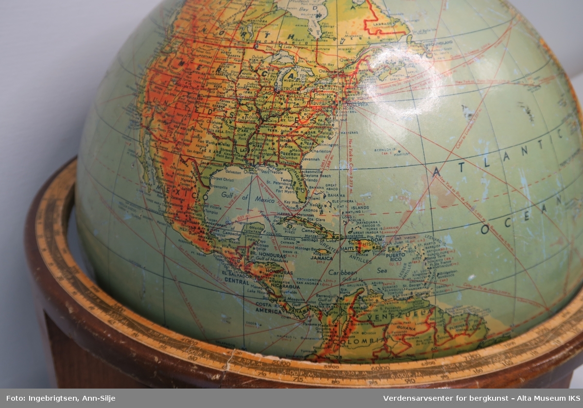 Globus med kart i farger og stedsnavn på engelsk. Beholderen er i tre, med fire buede foter under og en sirkelrund kant oppå disse fotene.