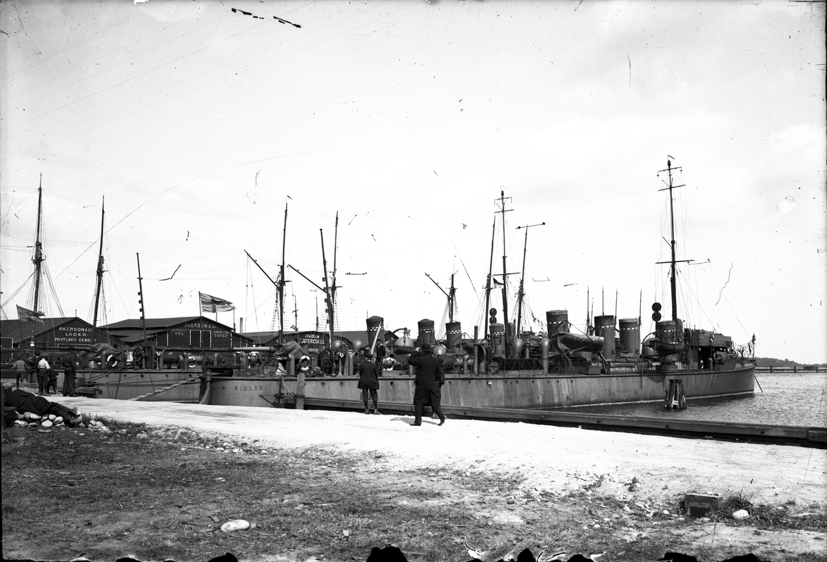 Jagaren HMS Sigurd (byggd 1908) i Gävle hamn. Åkerson & Co och J.E.M Delins kolmagasin i bakgrunden.