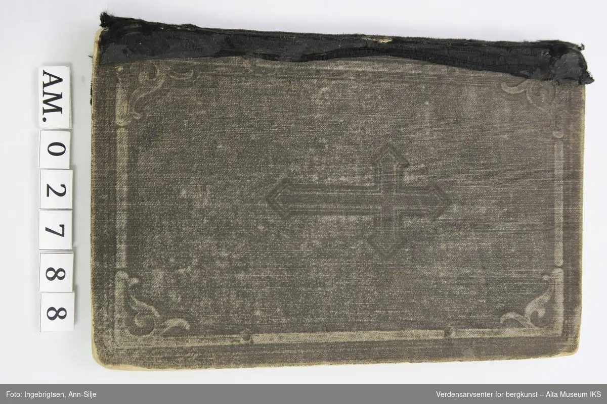 Form: Innbundet bok. Latinsk kors på frontperm. Teksten i boka er trykt med gotiske bokstaver.
