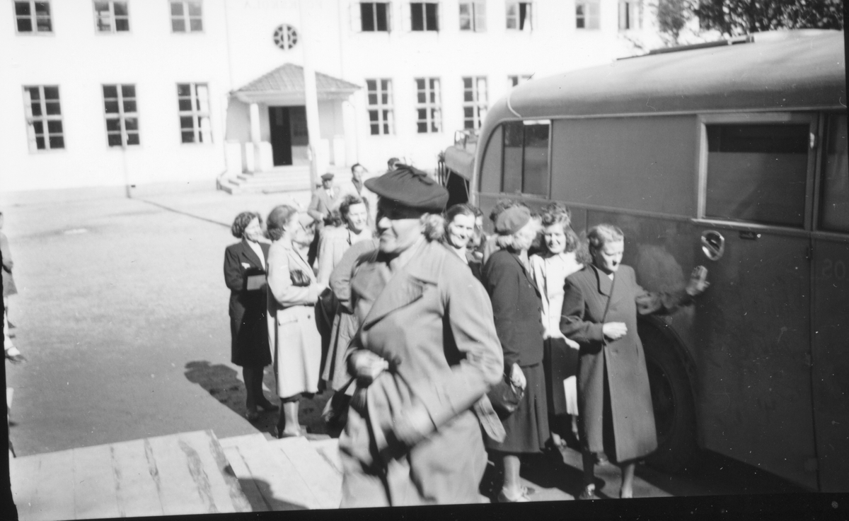 Grupp kvinnor framför buss och Södra skolan, Edsbyn. 

Hägers beskrivning:
Bilder från byn, skärmbildning
Edsbyn