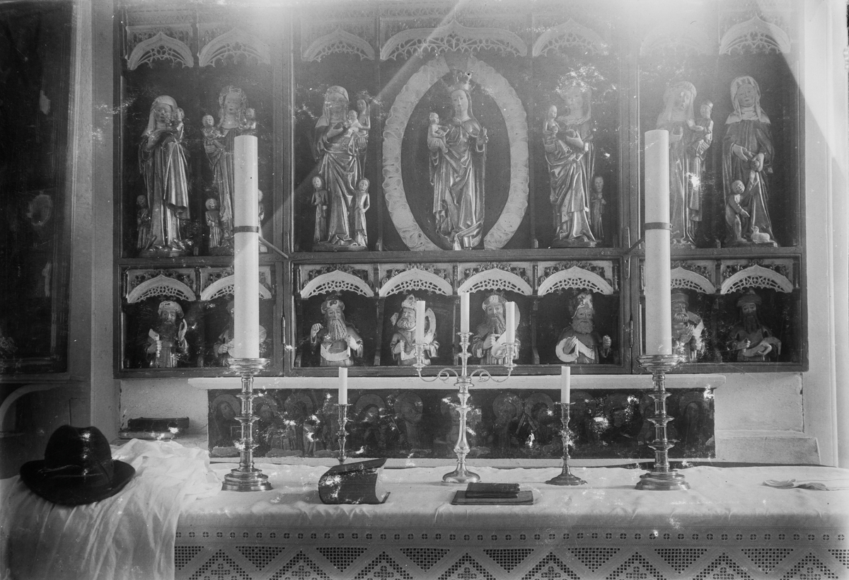 Lysestaker, bibel og en hatt foran den midtre altertavlen i Trondeneskirka.