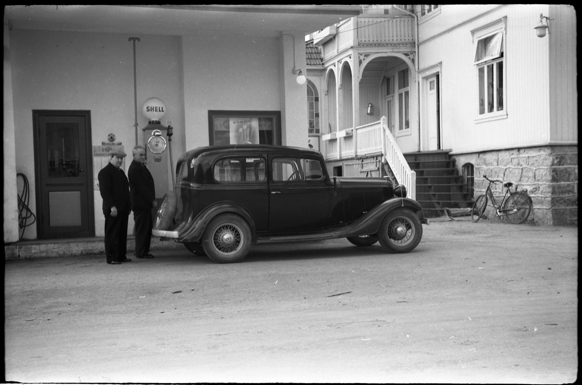 To bilder fra Lena sentrum mai 1938. Bildene er tatt ved den gamle Shell bensinstasjonen som lå der Lena Jernvare nå holder til. Ingen av personene på bildene er identifisert, men bilen er ifølge informant en Chevrolet 1933 Standard.
