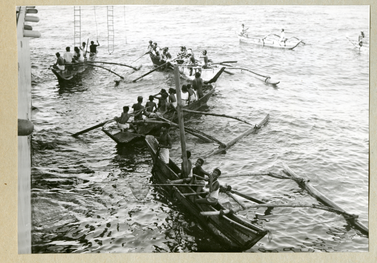 Bilden föreställer en nyfiken lokalbefolkning i flera kanoter vid minfartyget Älvsnabbens sida under långresan 1966-1967.