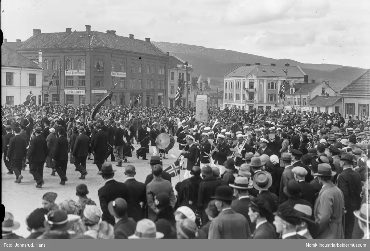 17. mai 1933. Folketog med korps gående i front ved Notodden torg. Hotell Bondeheimen i bakgrunnen
