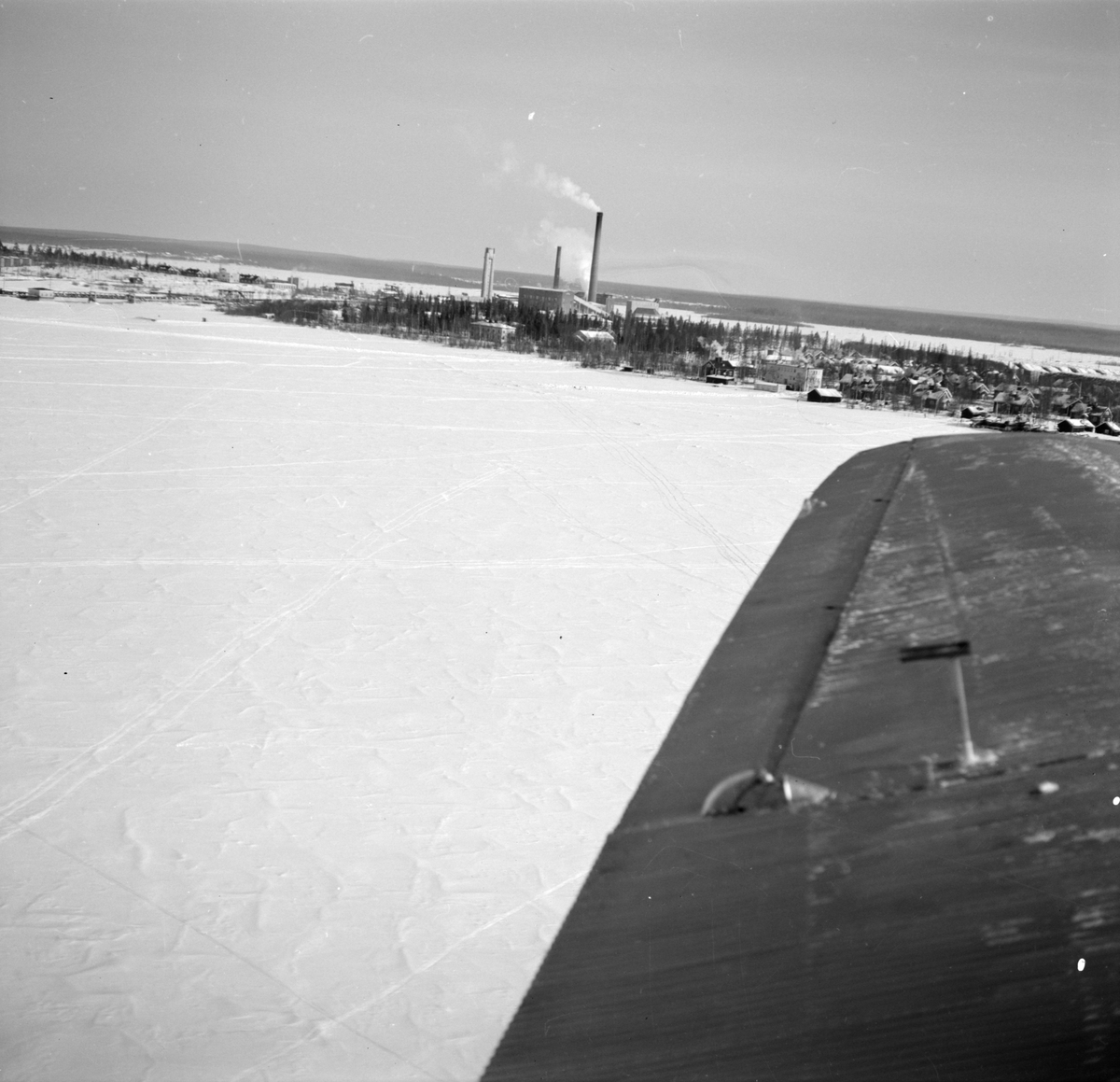 Flygfotografi av Veitsiluoto samhälle. Bild från F 19, Svenska frivilligkåren i Finland. Med flygplansvinge av flygplan Junkers F-13 i förgrunden.