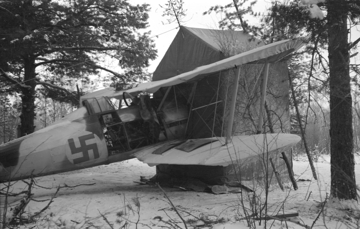 Flygplan Gloster Gladiator märkt gul I, tillhörande F 19, Svenska frivilligkåren i Finland, står med motorn i ett tält.