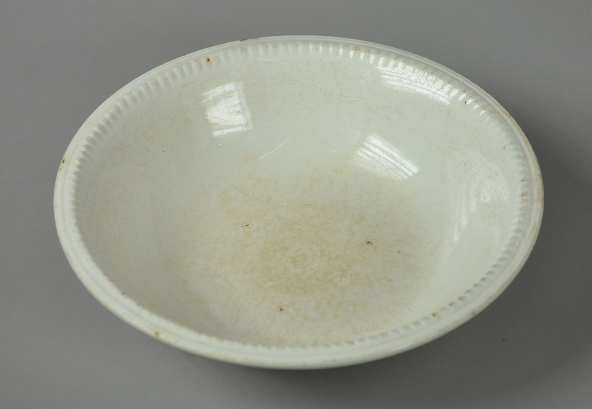 Rundt serveringsfat av glassert keramikk, med ruglete kant.