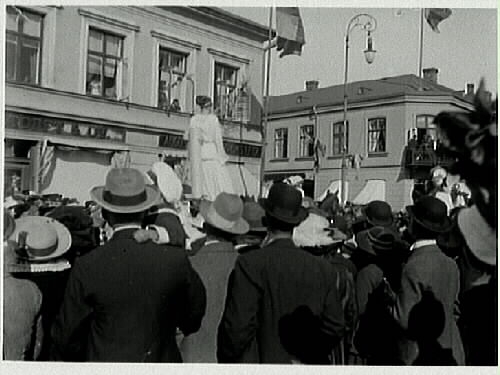 Karnevalståg med kvinnor på en stadsgata, eventuellt i Laholm. Finklädd publik kantar gatan. (Se även E5404.)