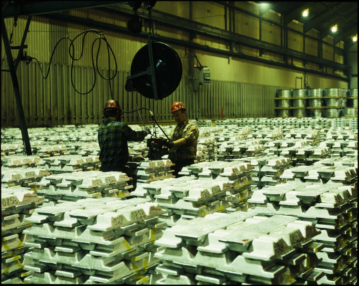 To menn arbeider i et lokale fylt opp av aluminiumsblokker ved Hydro sitt aluminiumsverk på Karmøy.