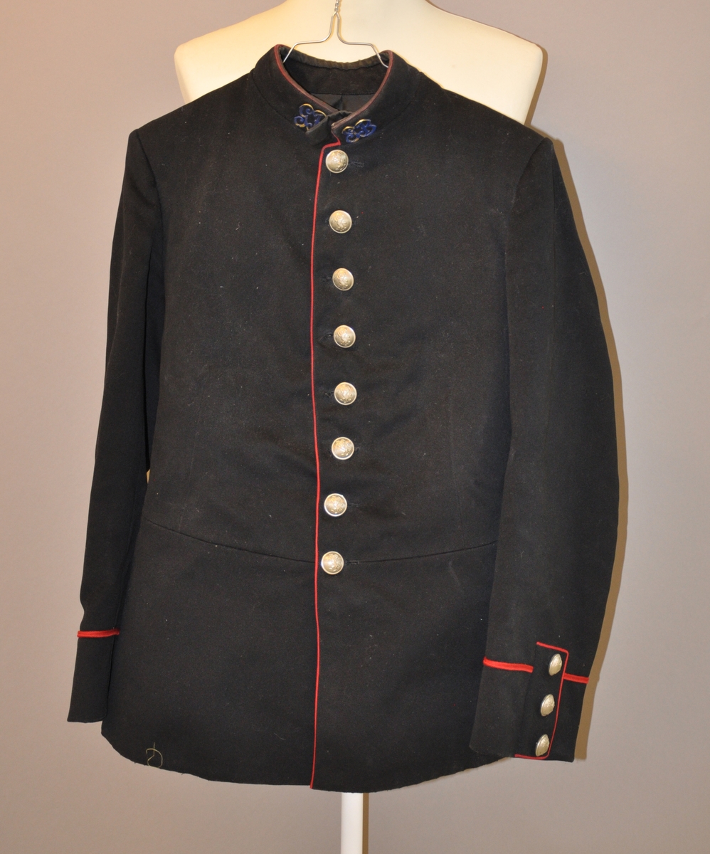 Uniformsjakke, våpenfrakk for infanteri fra Gundbrandsdalske Bataljon av svart ull. Jakken er innfelt med silke og har 8 sølvfargede knapper med det norske riksvåpnet som motiv på framsiden. På ærmene er det en enkelt rød galoner på hver side.