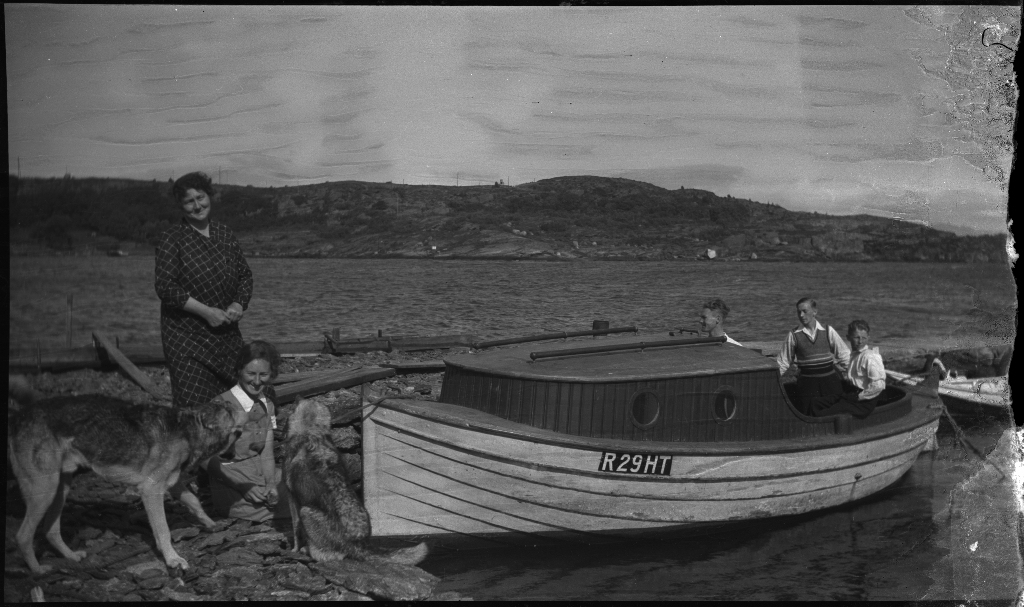 Familien Kamsrud på Tunsøy. Det er bilder av familien ved båten, av Annie Kamsrud og moren, Bertrand Kamsrud (i hvite klær) og to gutter til og hundene deres.