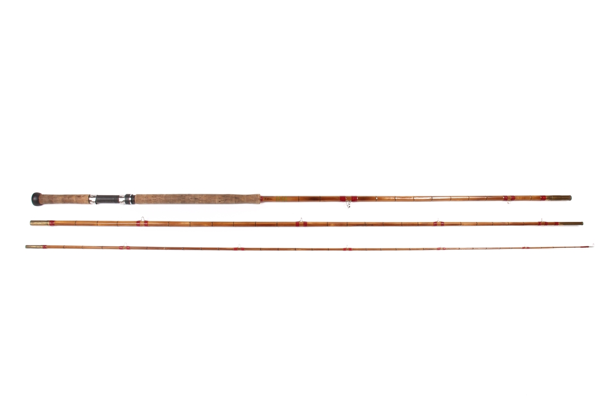 Tredelt fiskestang av type tohands splitcane med ekstra tupp og futeral. Den sekskanta stanga er laga av bambus og handtaket av kork.