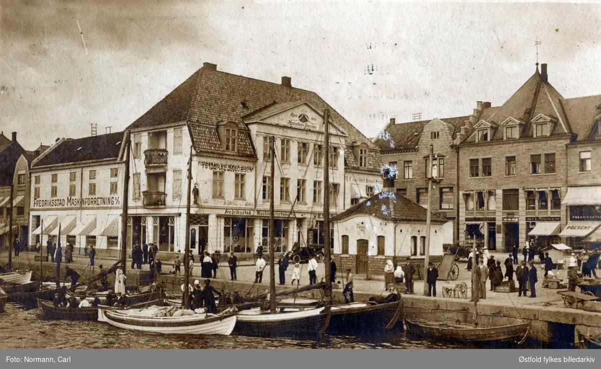 Parti fra Storgata i Fredrikstad med fisketorvet. 
Hanshusgaarden anno 1909 til venstre (hvit bygning) med Fredriksstad Maskinforretning A/S, i andre etasje reklame på veggen for fotograf Thendrup Jensen om Hjørnet.