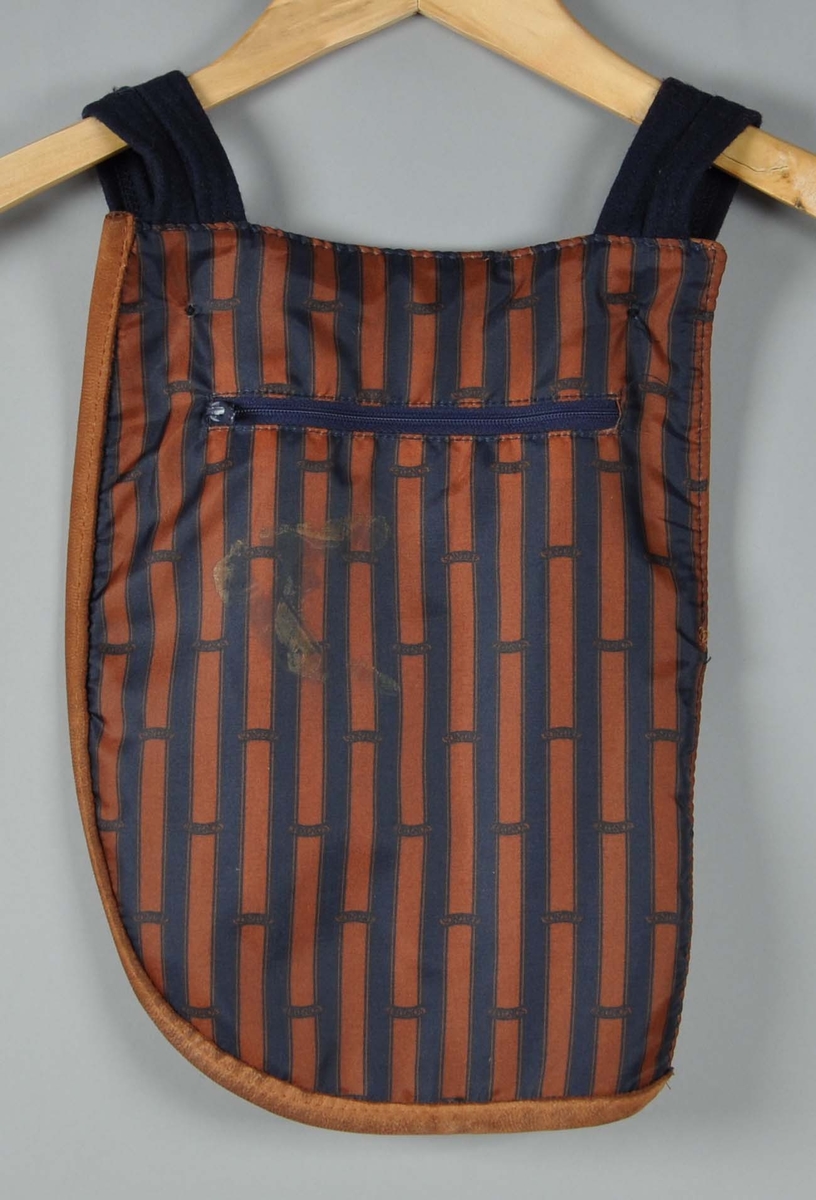 Taske i mørkblått ullstoff,dyp lomme i front kantet med skinn,glidelåslomme sydd i foret på baksiden.