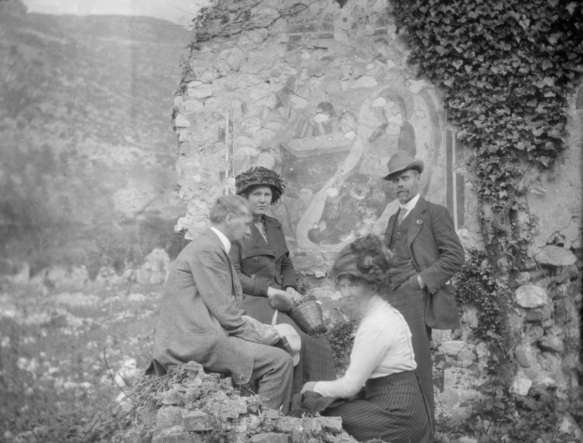 To kvinner og to menn på utflukt, fotografert foran en vakker steinmur
