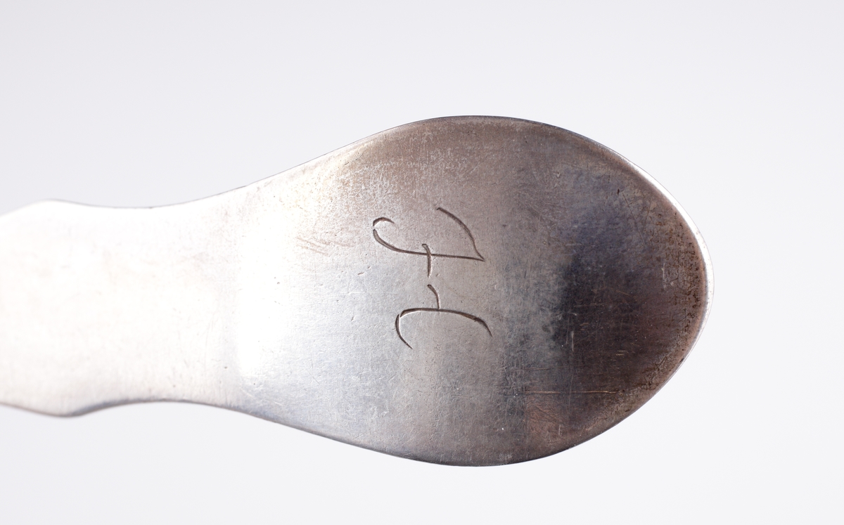 Matsked i silver, 
Fiolmodell, slät. Ägarinitial: "H" på baksidan av skaftet. Stämplar på baksidan av skaftet.