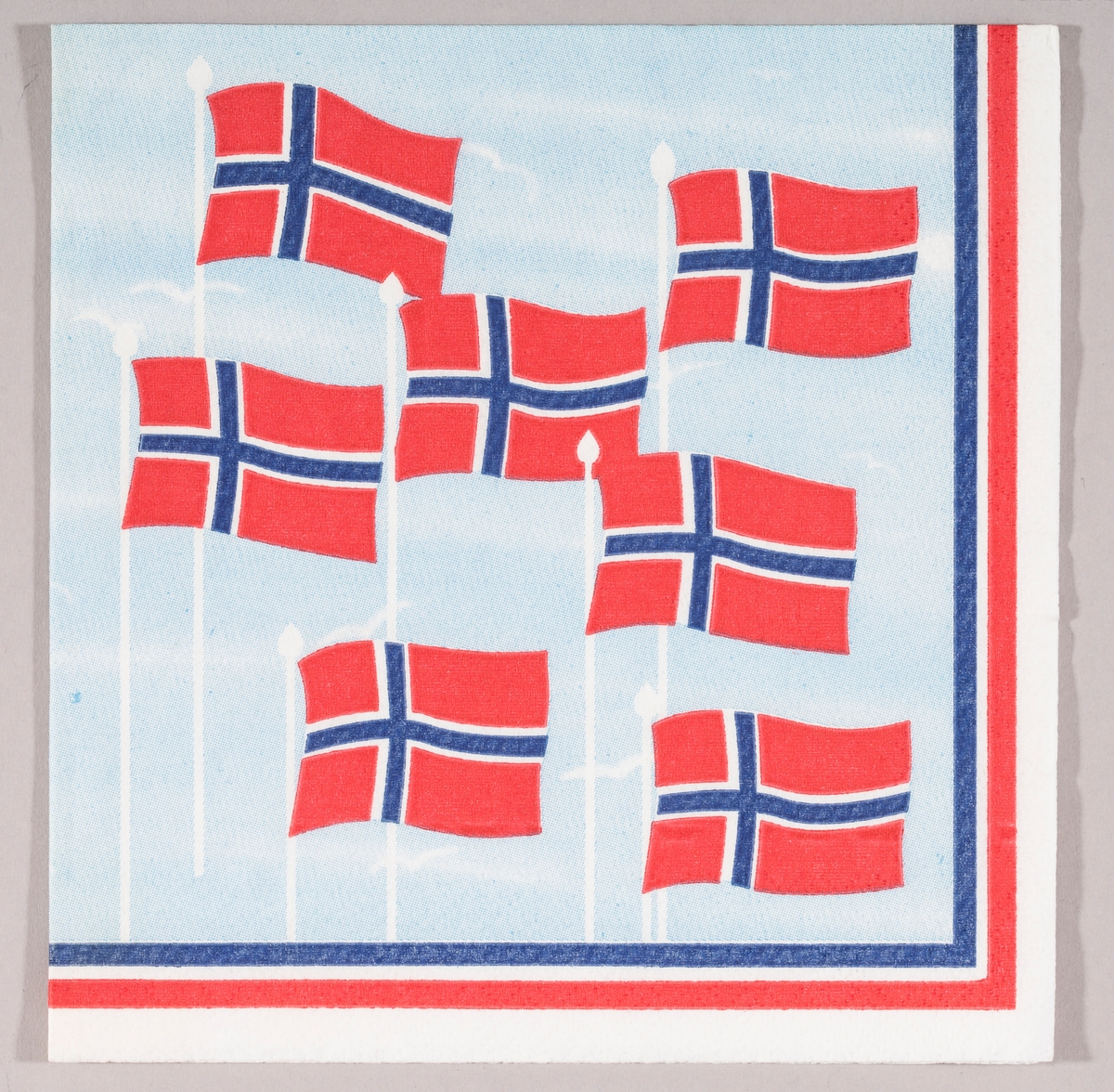 Norske flagg som flagrer i vinden mot en lysblå himmel
