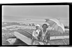 Hilda Sundt, med parasoll, og sønnen Rolf Jr. sitter på en r