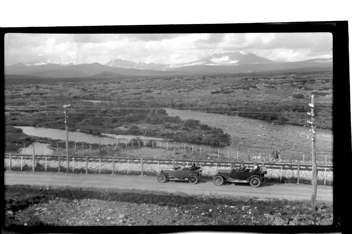 To biler, eid av henholdvis Halfdan Sundt og Rolf Sundt Sr., på fjellvei langs jernbanelinjen på Dovre. Fotografert 1925.