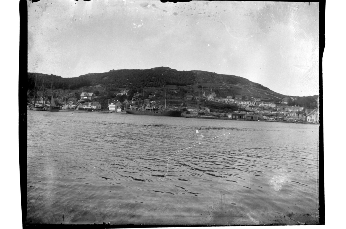 Utsikt fra sjøen mot Svinehagen etter bybrannen i Farsund. Et forsyningsskip ligger ved kai. Fotografert 1901.