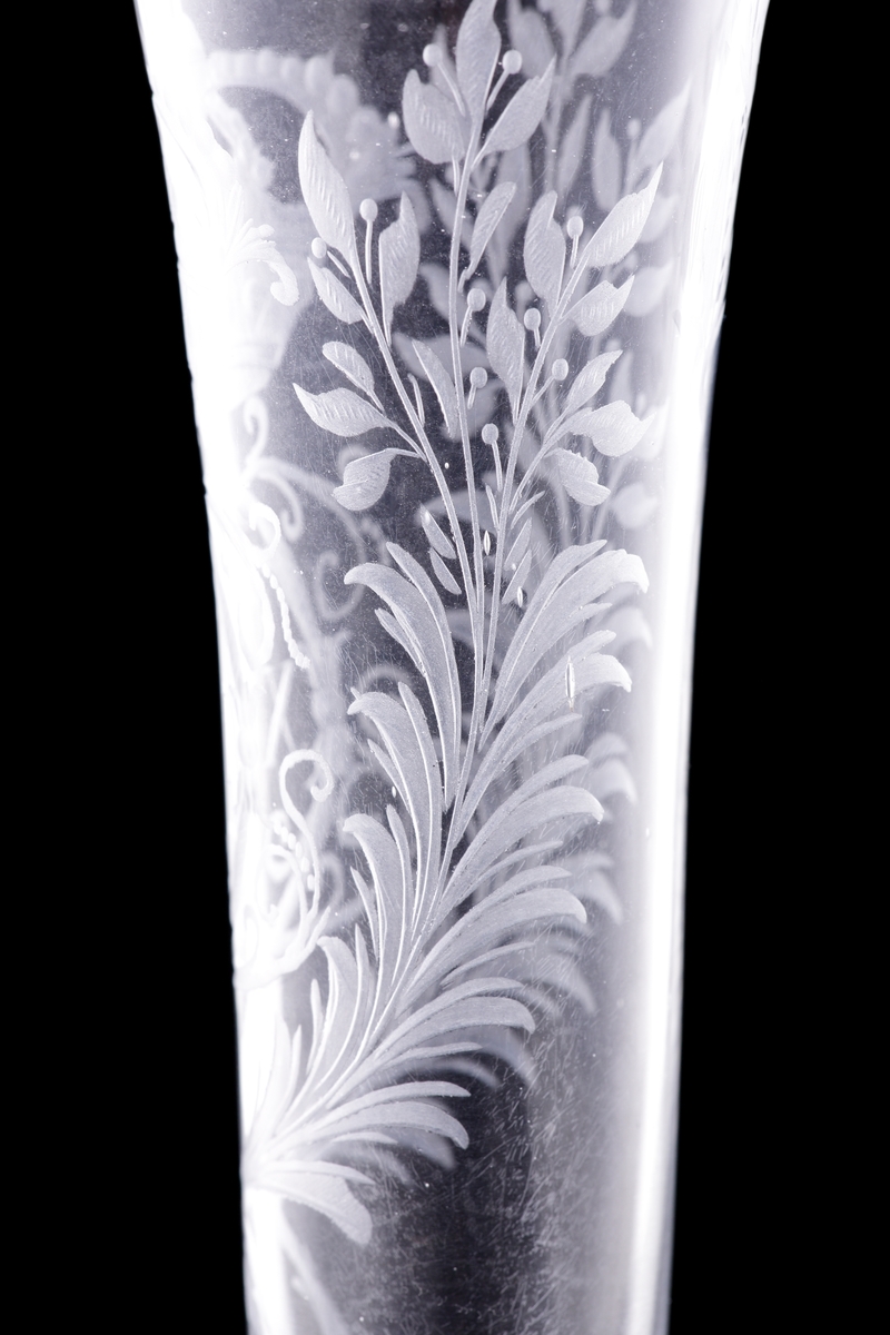 Champagneglas/strut på fot med omvikt kant.
Graverat spegelmonogram under kunglig krona: "C XIII"* med lagerkrans m.m.. 

* Carl XIII (1748-1818, reg. 1809-1818)