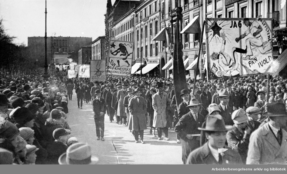 1. mai 1926, demonstrasjonstoget på vei nedover Karl Johans gate. Paroler: Jag fascistene fa'n ivold! - Leve den kinesiske frigjørelseskamp! - Leve den kommunistiske Internasjonale!
