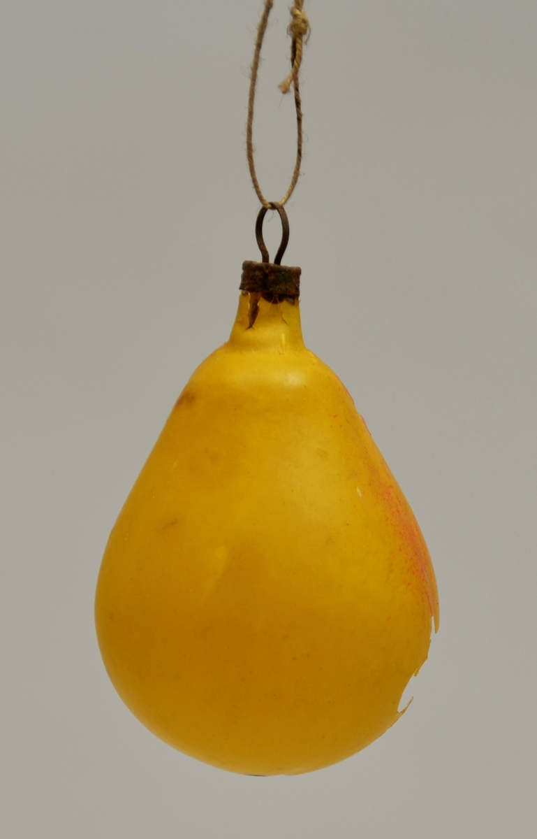 Julekule forma som ei pære, gul med litt raudt på eine sida. (Har eit knust hol og påsøla stearin)