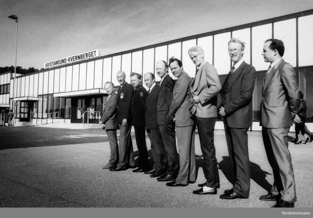 Foto fra en rekke personer ved Kvernberget lufthavn på Nordlandet i Kristiansund. Bildet er datert til 13. april men årstall mangler. Bildet er trolig fra perioden 1987 til 1990. Fotoarkivet stammer fra Nordmørsposten, og inngår nå i Nordmøre museums fotosamlinger.