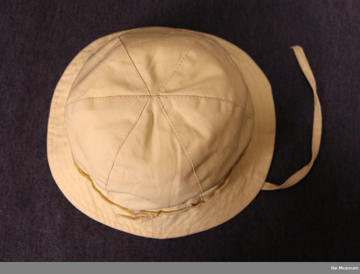 Hatt med brem til barn. Hatten har rund form, øyreklaffar og to snorer til å knyte under haka. Pullen er sydd saman av seks tøystykker.