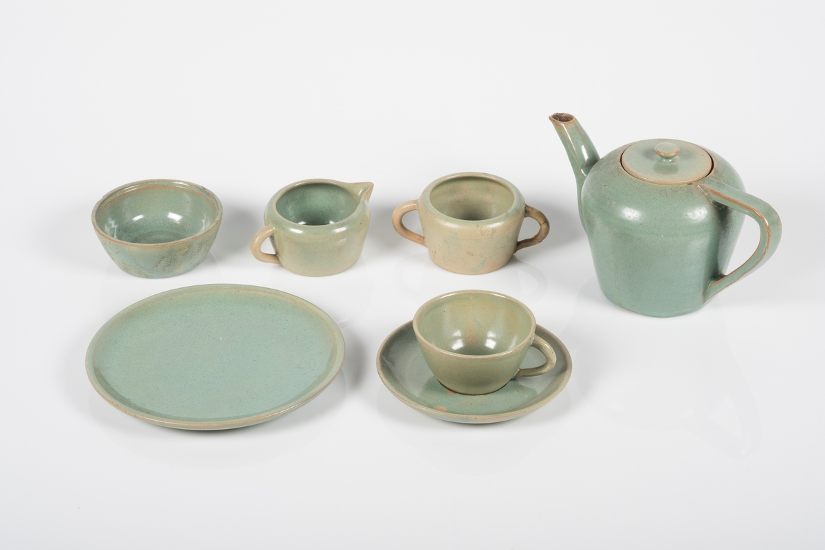 Teservise i keramikk med grønn lasur. 
Settet består av 22 deler; 1 tekanne, 6 kopper med 6 skåler, 6 tallerkner (asjetter), 1 fløtemugge, 1 sukkerkopp og 1 skål.
Grinisymbolet på bunnen av tekannen.