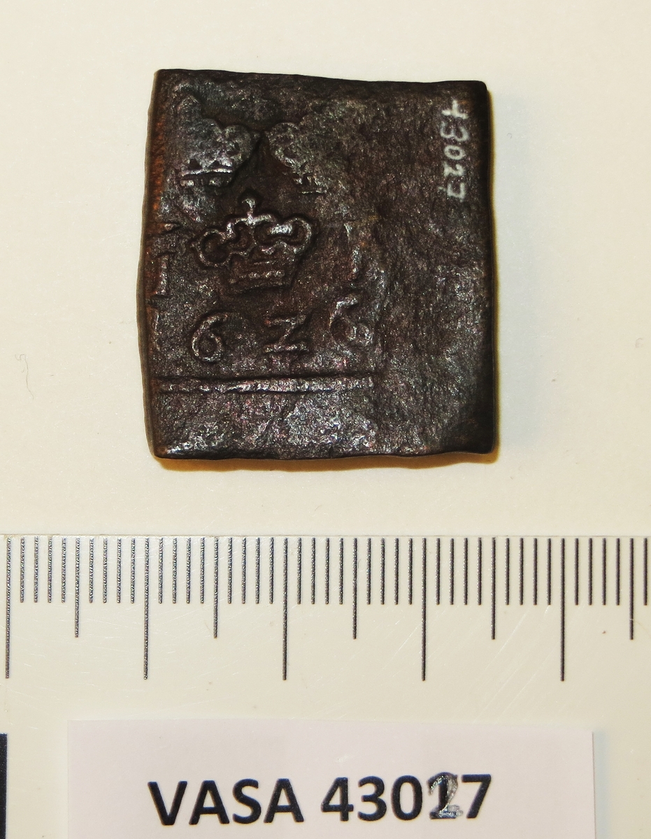 1- öre
Fyrkantigt mynt.
Åtsidan: tre kronor placerade i V-form, svagt synliga. Versalerna G och R svagt synliga. G till vänster och R till höger om kronorna.
Det fyrsiffriga präglingsåret - längst ner på myntet - är svagt synligt, 1626.
Ocentrerad prägling. Ram delvis synlig.
Frånsidan: två korsade pilar under en krona, delvis synliga.
Till höger om pilarna versalerna ÖR.
Ocentrerad prägling. Ram delvis synlig.
Nuvarande skick: bägge sidor delvis slitna. Frånsidan något krackelerad.
Vikt: 26,5 gram.

Text in English: Square-shaped coin. Denomination: 1 öre.
The obverse side has three crowns spaced in a V-shape, faintly visible. The letters G and R are faintly visible. G to the left and R to the right of the crowns.
The four digit year of coinage, 1626, is placed beneath the crowns and the letters. The date is faintly  legible.
The coin stamp is off-centre. The frame is partly visible.
The reverse side has two crossed arrows beneath a crown, partly visible .
To the right of the arrows are the letters ÖR.
The coin stamp is off-centre. The frame is partly visible.
Present condition: both sides are partly worn. The reverse side has a craquelure-like surface.
Weight: 26,5 gram.
