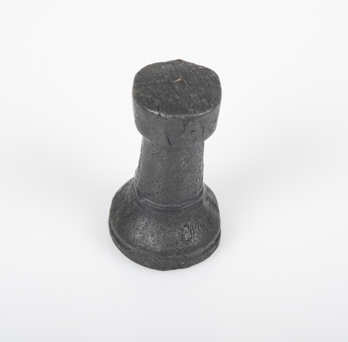 Sjakkbrikken (tårn) er laget av tre, og er malt svart. Toppen er flat. Et lite avlangt hull på undersiden.