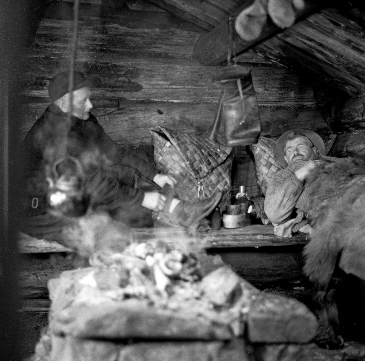 Kviling i koie, antakelig den såkalte «bjønnbua» på Norsk Skogbruksmuseum. Karene på koiebriskene er Ivan Sandberg og Martinus Nordal, og bildet er antakelig tatt i forbindelse med innspillinga av dokumentarfilmen «Liv og husvær i skogen», antakelig vinteren 1961-62.  Karene hadde gjort opp varme på eldpallen, og det hang en kaffekjel i ei skjæring ned over varmen.  Sandberg satt på brisken i vadmelsklær, tilsynelatende i ferd med å ta av seg våte sko, mens Nordal hadde lagt seg på brisken, under en skinnfell.  Begge hadde neverkonter. 

Martinus Nordal var skogsarbeider, som også markerte seg med et engasjement i fagorganisasjonen «Skog og Land».  Da dette fotografiet ble tatt var han om lag 72 år gammel og dermed pensjonist, men han stilte opp da man trengte aktører til en film om skogsarbeidernes arbeids- og levekår.  Filmen fikk tittelen «Liv og husvær i skogen».

Litt biografisk informasjon om Martinus Nordal finnes under fanen «Opplysninger».