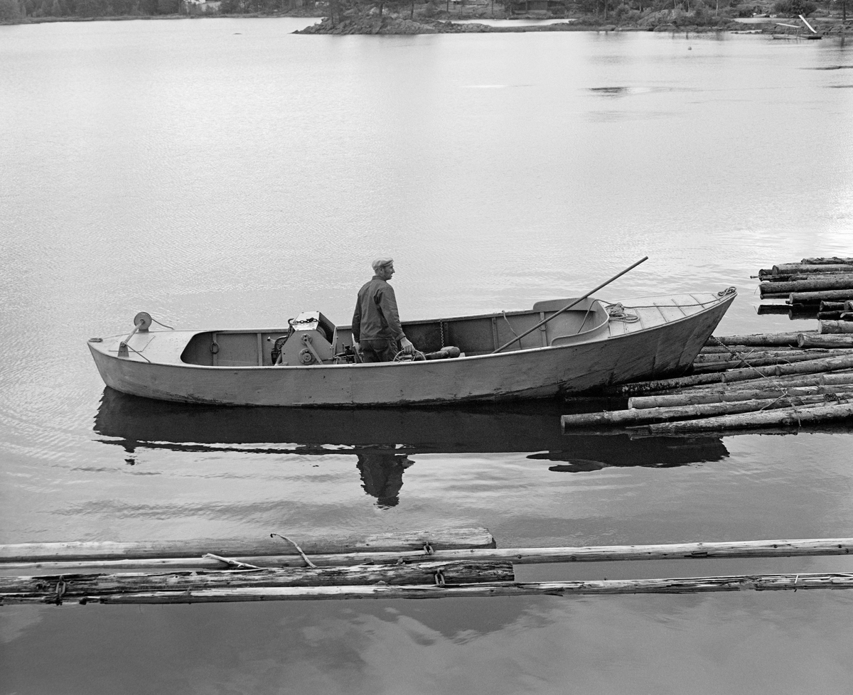 Varpebåt av stål, fotografert ved innløpet til Ørje sluser i Marker kommune i Østfold (Haldenvassdraget). Mannen i båten er Einar Melby (1915-2003), som i mange år arbeidet for Haldenvassdragets Fellesfløtiningsforening nettopp ved Ørje.  Båten ble brukt til sleping, og varpespillet vi ser bak ryggen til Melby gjorde nytte for seg dersom noe satte seg fast.  Dette fotografiet er tatt i 1982, den siste sesongen det ble fløtet tømmer i Haldenvassdraget.  

Det første sluseanlegget ved Ørje ble bygd i perioden 1857-1860, og fra 1877 ble tømmer fra de øvre delene av vassdraget fløtet ned til industrien i Halden på et kanalisert vassdrag.  En kort historikk om fløtinga i Haldenvassdraget finnes under fanen «Opplysninger».