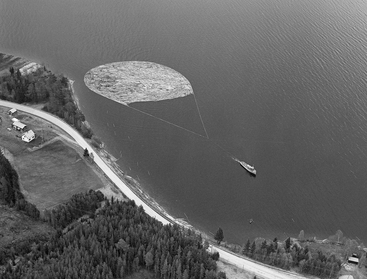 Flyfotografi, tatt over Fiskvikstøa i Ytre Rendalen, på Storsjøens vestside i 1981.  Vi ser hvordan riksveg 30 (her også kalt «Gamle kongeveg») slynget seg langs strandlinja. Mellom vegen og strandlinja, øverst til venstre i bildet, lå det en utislagsplass for tømmer som ble transportert til hovedvassdraget på lastebiler.  På vannspeilet ser vi en ringbom som ble slept sørover av tømmerslepebåten «Storsjø».  Det tok vanligvis drøyt 30 timer å trekke en slik ringbom fra området ved Åsheim i nordenden av innsjøen til utløpet i elva Søndre Rena, om lag 36 kilometer lengre sør.  Med de store tømmermengdene som ble fløtet i 1950- og 60-åra ble det gjerne omkring 30 turer, og sesongen varte om lag to måneder.  Da dette fotografiet ble tatt, i 1981, kunne 10-12 ringbommer romme det tømmeret som skulle fløtes ut av Rendalen.  Virksomheten ble avviklet etter 1984-sesongen.