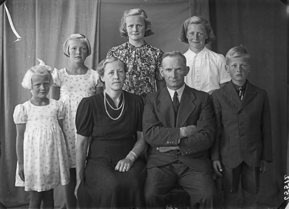 Gruppebilde. Familiegruppe på syv. Kvinne og mann sittende foran, fire piker og en gutt stående bak. Bestilt av Hr. lensmand Robberstad