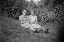 Foto av to kvinner sittende på plenen, trolig hjemme på fami