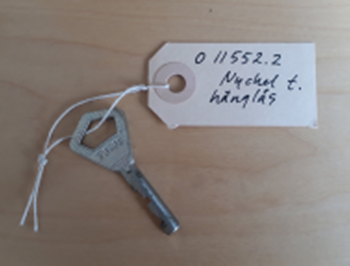 Nyckel till hänglås märkt F 3433. Även nyckeln märkt F 3433.