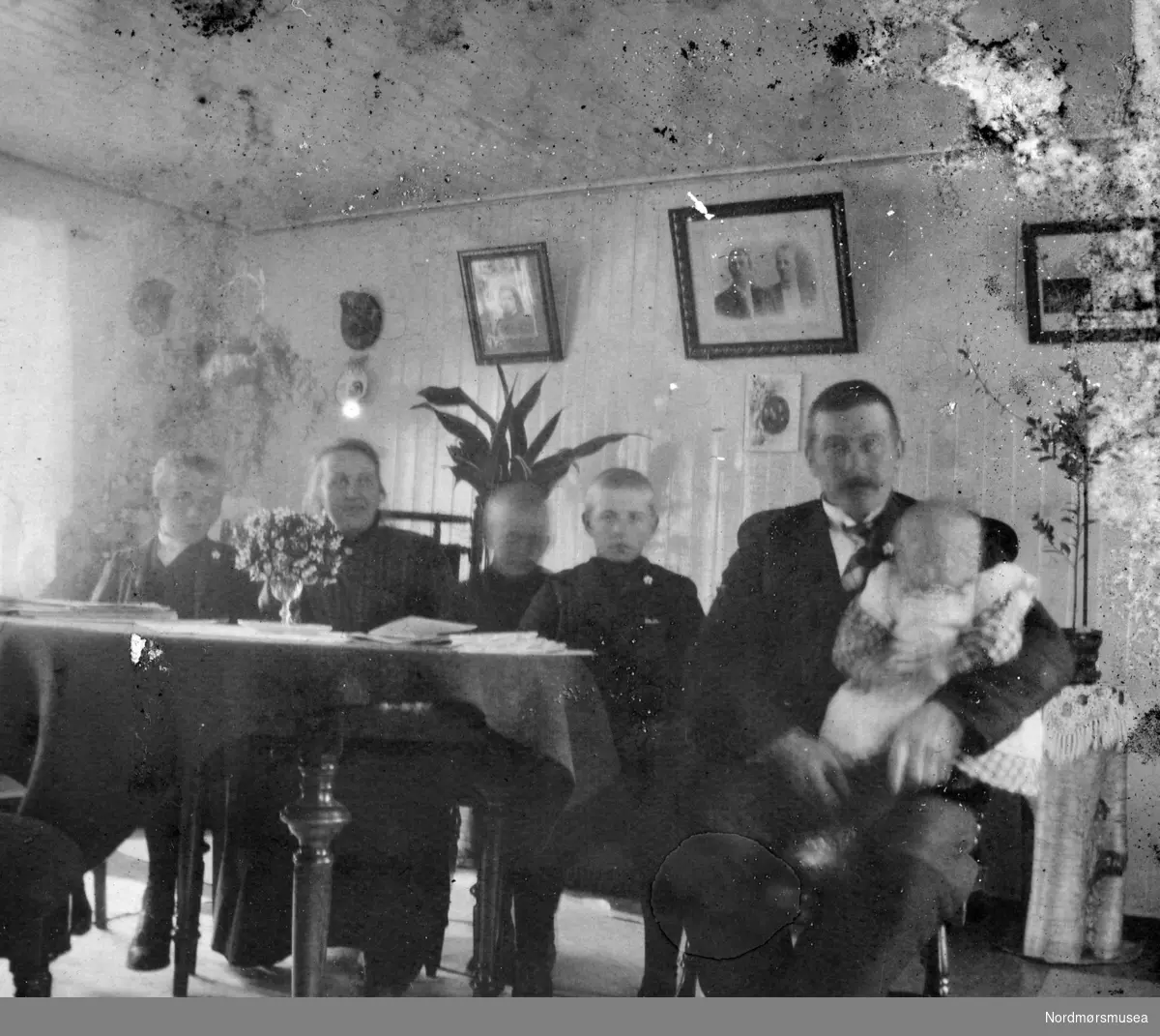 Foto av et ektepar i stuen sammen med sine fire barn. Samling fotografier fra Enge Bruk i Valsøyfjord i Halsa kommune. Eier av originalmaterialet er Kolbjørn Botten. Fra Nordmøre museums fotosamlinger.