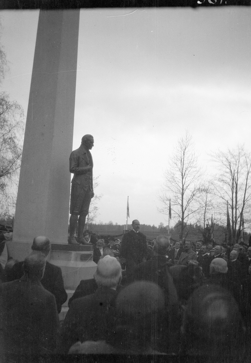 Grunnloven 100 år. Kong Haakon 7 taler ved avdukingen av Carsten Anker monumentet foran Eidsvollsbygningen, 17.mai 1914.