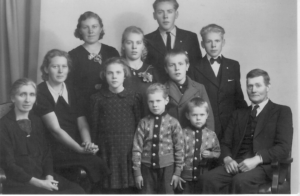 Familien til Maria f.Taksdal og Jens Serigstad på Serigstad bnr. 14. Dei to bak er Anna Serigstad g. Dahlen (7.5.1919 - 13.8.2005) og Einar Serigstad (15.2.1924 - 23.12.1970). Dei tre i rekkja framfor er f.v. : Gunnvor Serigstad g. Gausland (15.2.1922 - 17.10.2010), Målfrid Serigstad g. Løland (28.11.1926 - 12.5.2014), Karl Serigstad (21.9.1928 - 18.2.2019). Framfor der står Borgny Serigstad 17.11.1933 - ) og Jostein Serigstad (26.3.1931 - 28.6.2018). Dei to minste fremst er f.v. Martin Johan Serigstad (13.10.1936 - ) og Magnor Serigstad (13.3.1939 - ). På venstre side framme sit Maria Serigstad f. Taksdal (29.7.1894 - 12.9.1989) og på høgre side Jens Serigstad (15.10.1893 - 5.11.1980)
Retta 02.01.2020 etter brev frå Martin Johan Serigstad.
