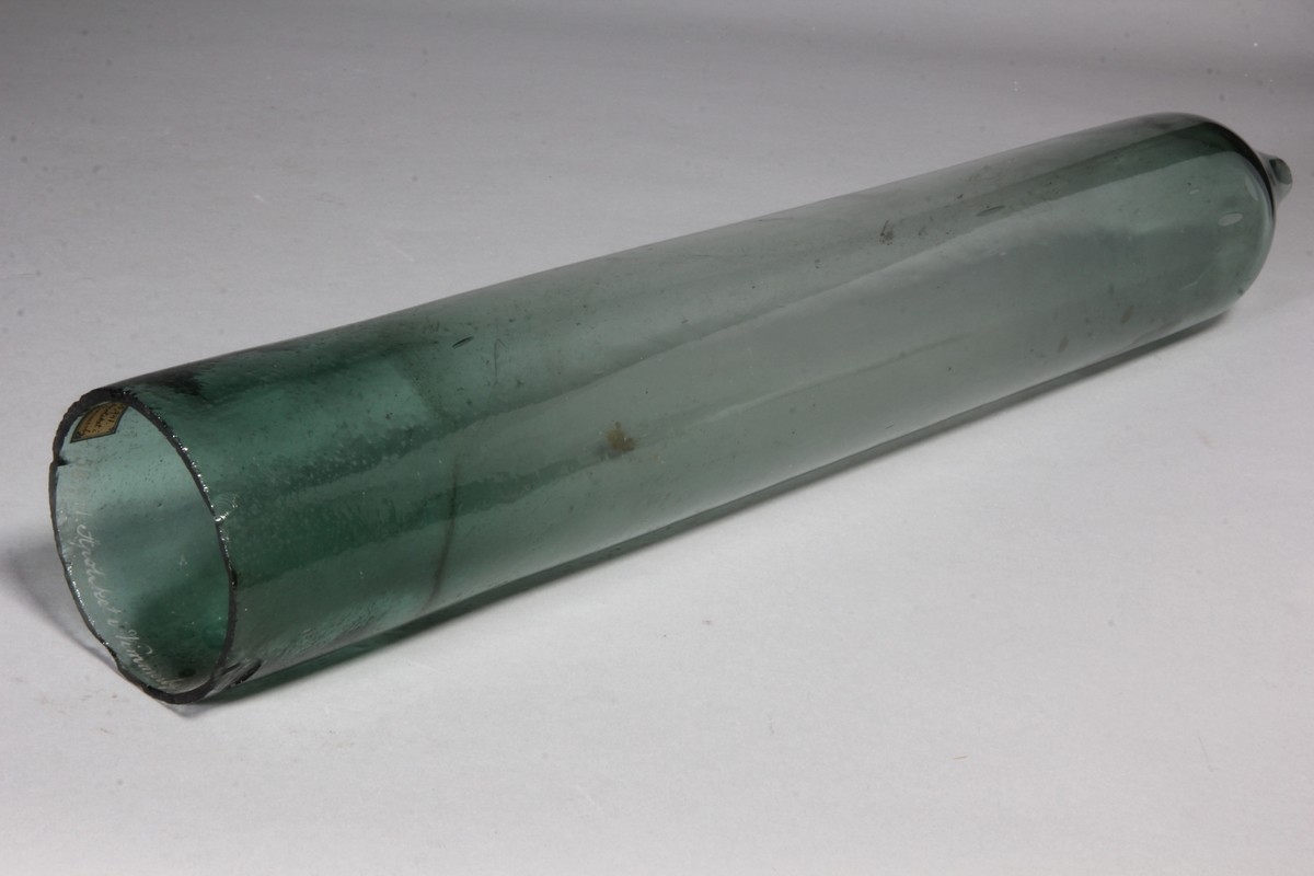 Retort av grönt glas, cylindrisk, avsmalnande i ena änden.