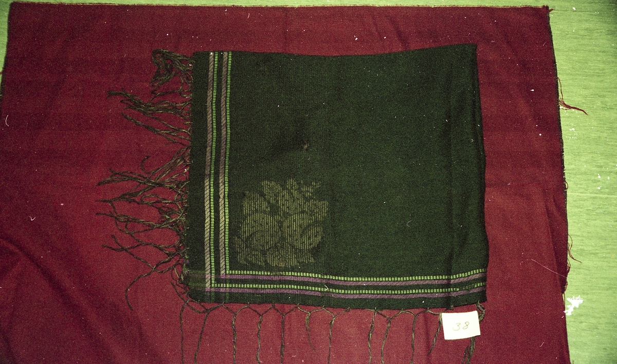 Et frynsa ullsjal med lilla og grønne border. Motiv tatt ved ei tekstilutstilling i Valldal.