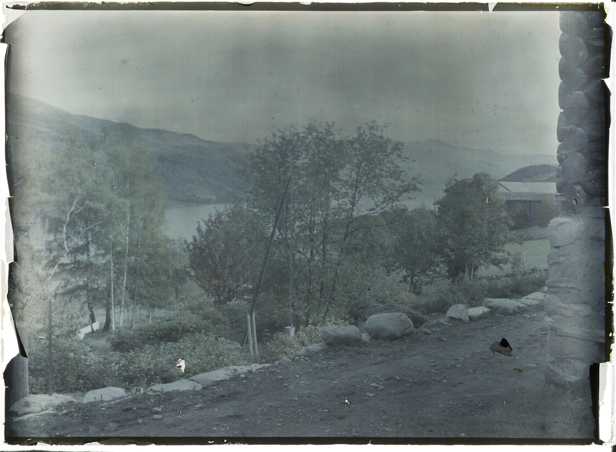 Vågå, ved Storvikgardene, utsikt mot Vågåvatnet, i front veg med heiseanordning for vannhenting i brønn. Uklart og slitt bilde