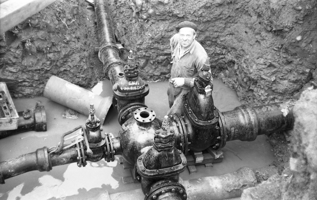 Rørlegger Arne Dahl hos Staff & Sønner i arbeid i vannverksgrøft, trolig i forbindelse med etablering av Skreia Vannverk september 1953. Fem nær identiske bilder.