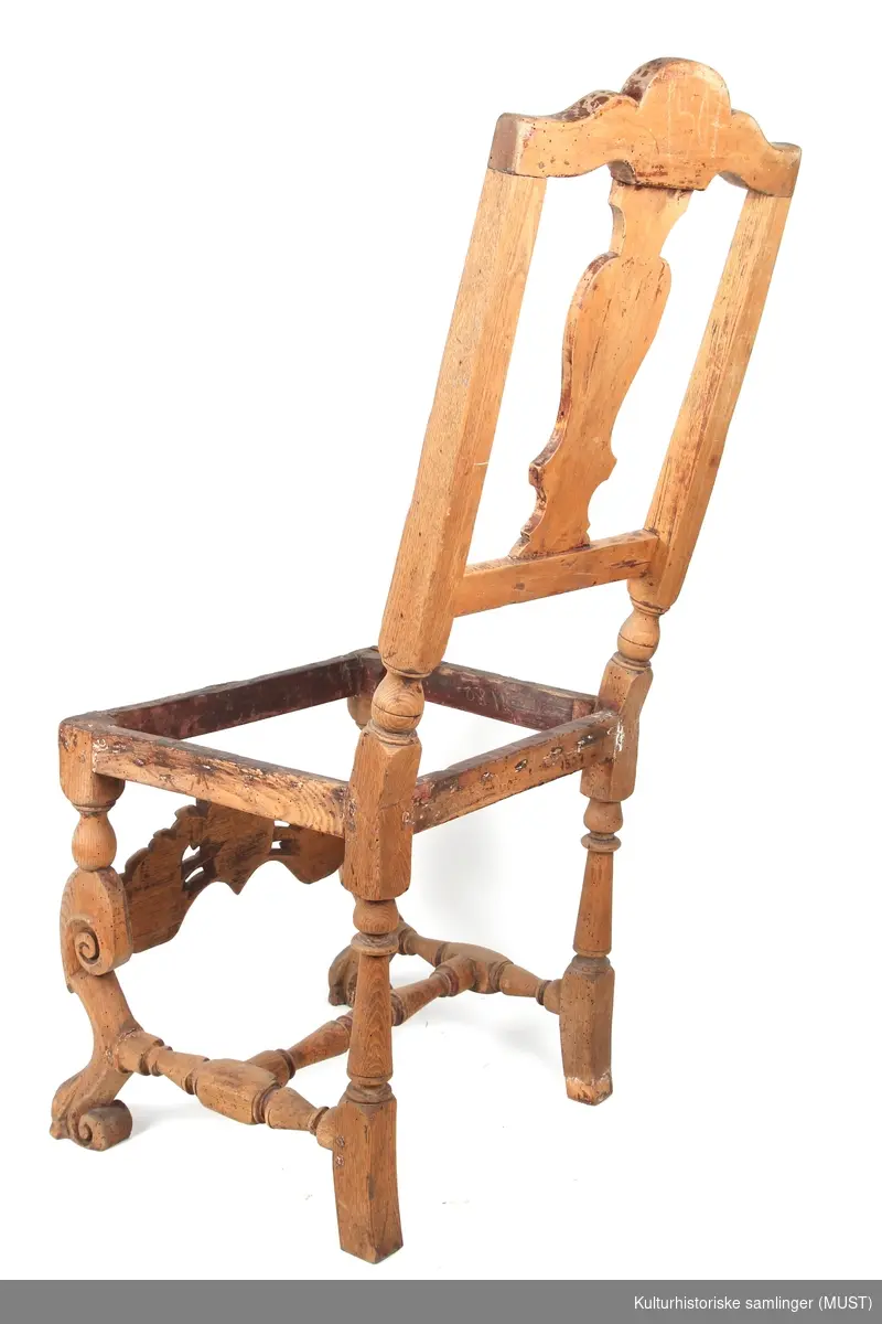Toppstykke med skjell som minner om rokokkostolens trekk. Dette tyder på at det er en barokkstol med sekundær rygg fra midten av 1700-tallet. Dette er antagelig gjort for å modernenisere stolen og tilpasse den til rokokkostil. 
Bindingsspross med utskjæring i form av krone og akantusblad. 
Løveføtter. Mangler setet.