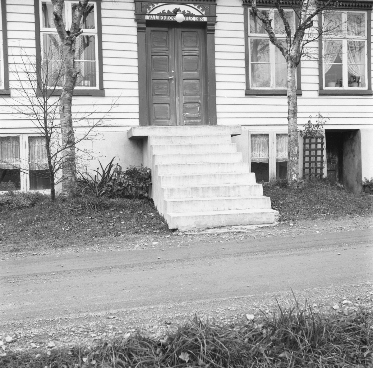 Motiv av inngangspartiet til et skolehus på Valderøy. På skiltet over døra står; "Valderøens skole 1869".