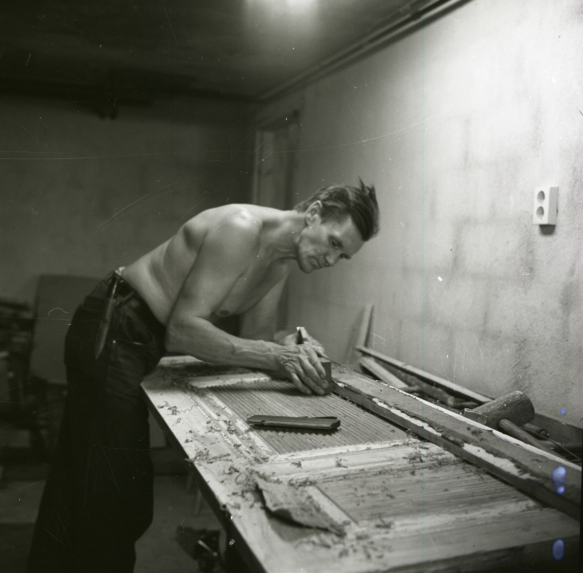 Hilding Mickelsson dekorerar en dörr i trä genom att göra fördjupningar omväxlande med förhöjningar, juni 1968.
