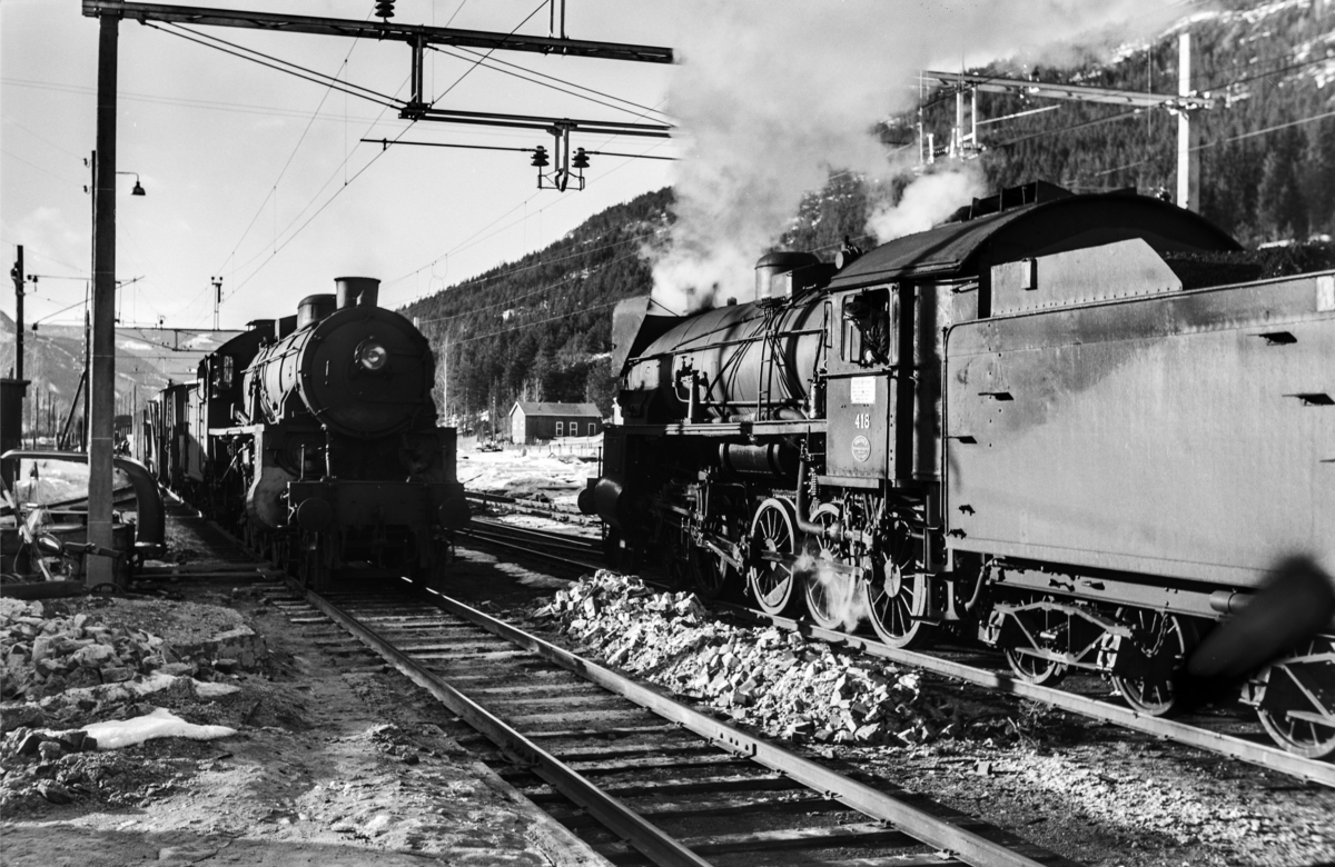 Kryssing mellom godstog til Bergen og godstog 5532 til Hønefoss på Nesbyen stasjon. Toget til Bergen trekkes av damplokomotiv type 31b nr. 418, tog 5532 trekkes av damplokomotiv type 31b nr. 449.